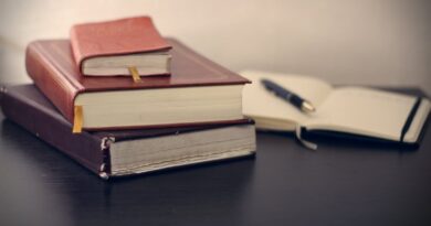 selective focus photography of three books beside opened notebook